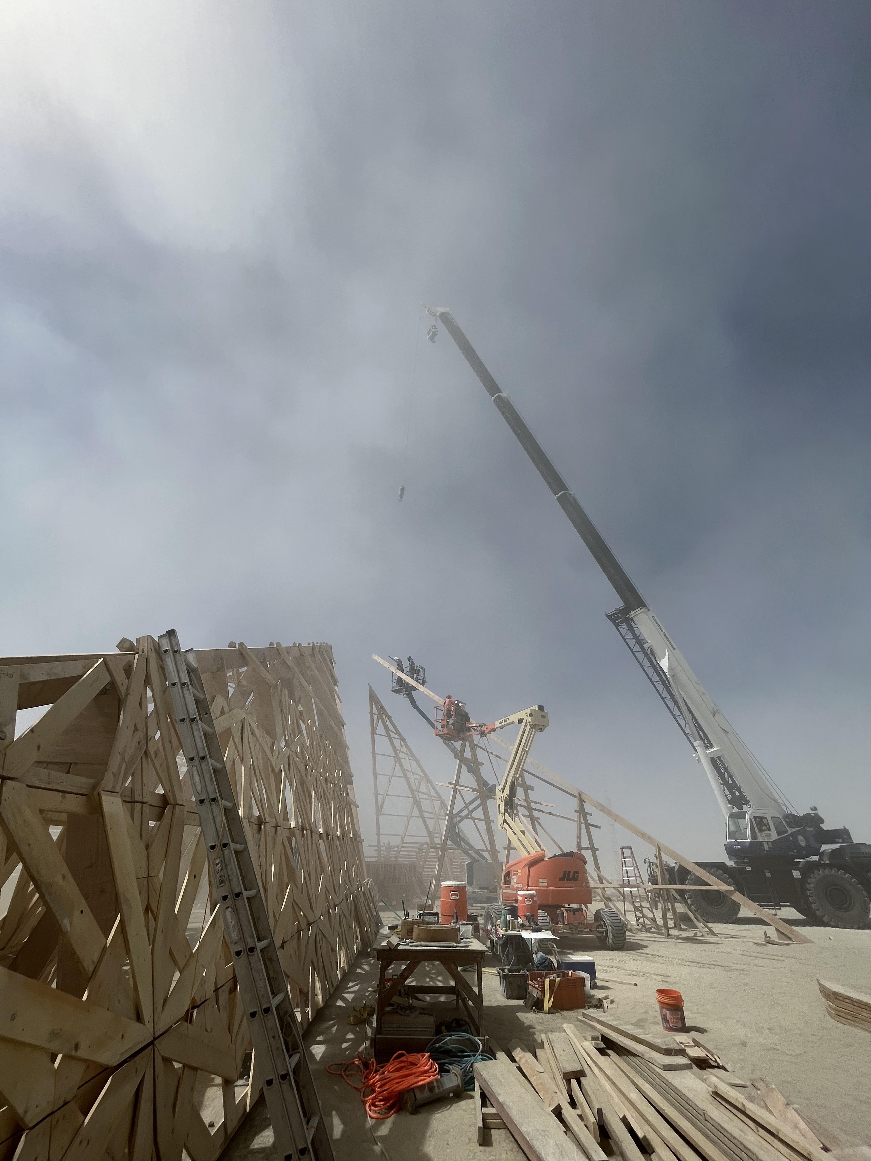 a crane stands above big wooden structure in the dust storm